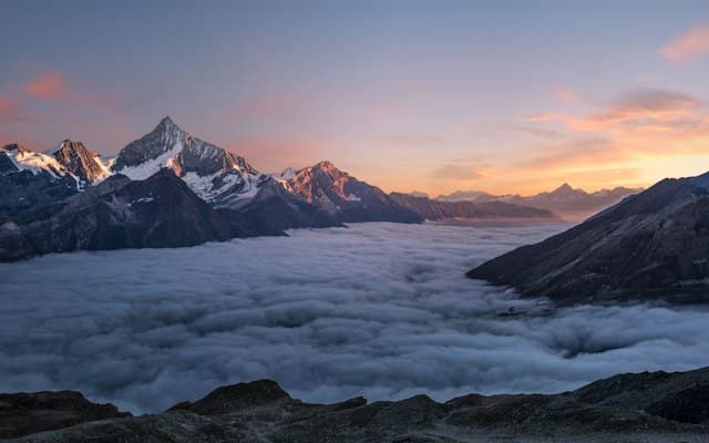 Aerial view of snow-capped mountains with golden light at dawn