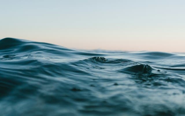 Ocean waves gently rolling onto a tropical beach at sunset